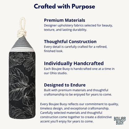 A black boujee buoy with a white botanical leaf pattern and a white rope loop, shown on a light gray background with descriptive text about premium materials, thoughtful construction, individual handcrafting, and designed endurance. The Boujee Buoy logo is visible in the bottom right corner.