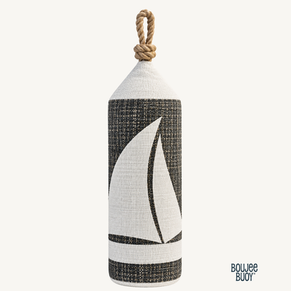 Boujee Buoy nautical decorative pillow shaped like a maritime buoy, featuring a white sailboat design on textured charcoal gray upholstery fabric, finished with a knotted rope handle and a solid wood base.
